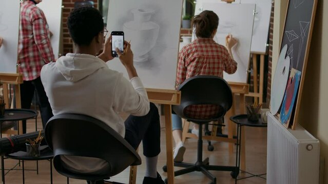 Artistic person taking photo of vase masterpiece on canvas. Art class student using smartphone to take picture of sketch after finishing drawing model, saving contemporary masterpiece.