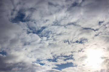 Bright sun behind white clouds. Sky background.