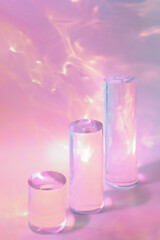 Abstract surreal scene - empty stage with three clear glass cylinder podiums on pastel pink...