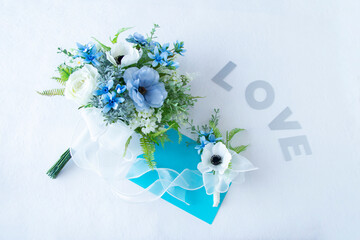 幸せを願う白と青のウェディングブーケとブートニアとLOVEの文字（アネモネ、バラ、ラナンキュラス、ブルースターなどの造花）