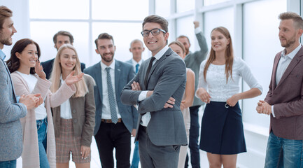 Obraz premium proud young businessman standing in front of his team