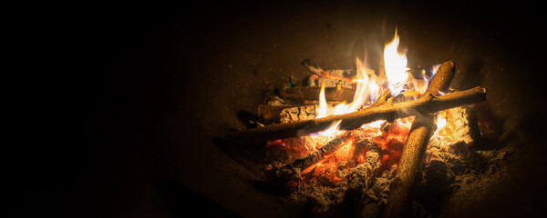 Bonfire, log fire, or campfire in dark background with flame, burned log wood, firewood in home...