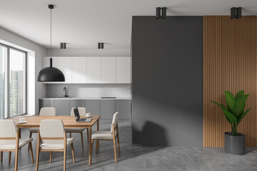 Grey kitchen interior with dining table and seats, window and plant. Empty wall