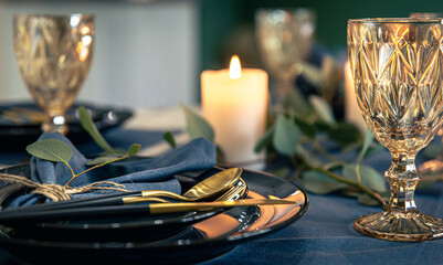 Table setting with textured wine glasses, candles and leaves.