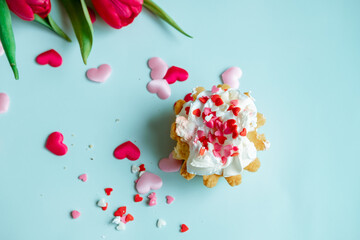 cake with whipped cream and red tulips on a blue background, top view