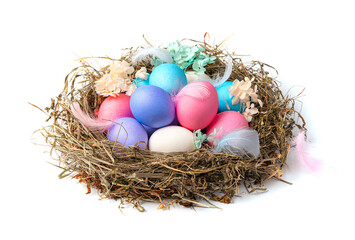 A large nest with colored Easter eggs in with feathers and flowers isolated on a white background.