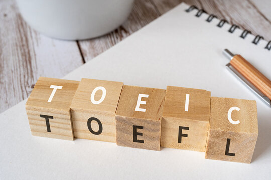 「TOEIC」「TOEFL」と書かれた積み木、ペン、ノート、コーヒーカップ