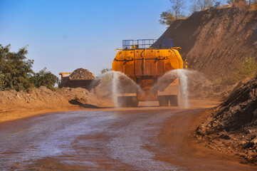 Heavy truck pours the road with water in the iron ore quarry. Dust removal, protection of the environment. Irrigation of the road from dust.
