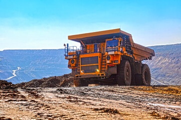 Mining dump truck transports rock, iron ore along the side of the quarry. © Yevhen