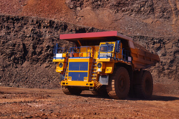 Mining dump truck transports rock, iron ore along the side of the quarry. © Yevhen