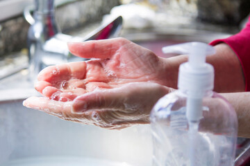 Hygiene. Hand cleaning. Wash hands with soap. Woman washing her hands with soap over the sink in the kitchen, closeup. Covid 19. Coronavirus.