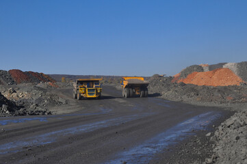  Mining dump truck transports rock, iron ore along the side of the quarry.
