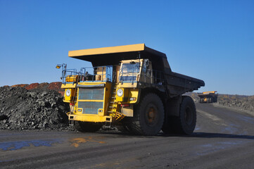 Mining dump truck transports rock, iron ore along the side of the quarry. © Yevhen