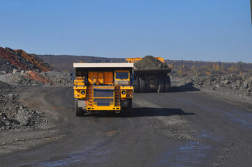 Mining dump truck transports rock, iron ore along the side of the quarry. © Yevhen