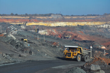 Fototapeta na wymiar Mining dump truck transports rock, iron ore along the side of the quarry.