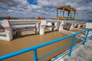 Shardara river dam. Concrete bridge, Gentry crane. Calm yellow water. Blue sky with clouds. Kazaly...