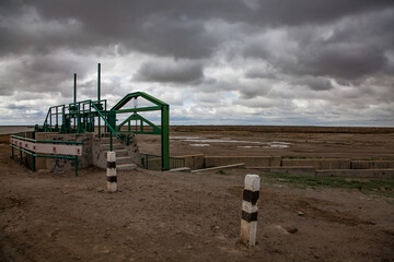 Aklak dam on Shardara river. Small manual water shutter. Dark grey storm clouds. Kazakhstan,...