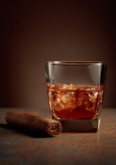 Whiskey with ice and cigar on a rusty background.