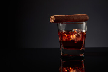 Glass of whiskey with ice and cigar.