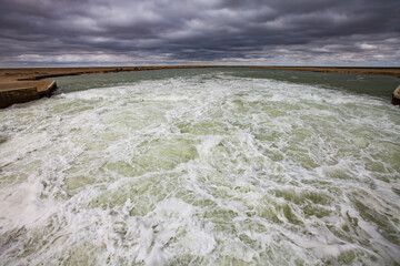 Aral Sea Kok-aral dam. Turbulent water after dam. Stormy clouds on horizon. Kzylorda region, Kazakhstan.