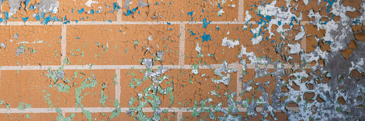 Peeling paint on the wall. Panorama of a concrete wall with old cracked flaking paint. Weathered rough painted surface with patterns of cracks and peeling. Wide panoramic texture for grunge background