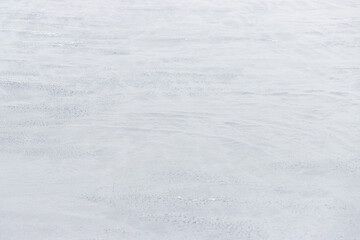 Beautiful winter background with snowy ground. Natural snow texture. Wind sculpted patterns on snow surface.