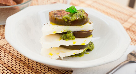 caprese salad with mozzarella, black tomatoes and pesto in white plate