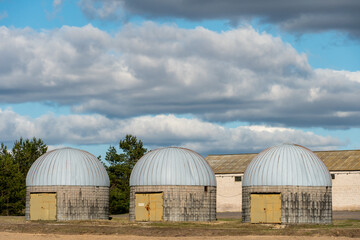 Obraz premium silver silos on agro manufacturing plant for processing drying cleaning and storage of agricultural products, flour, cereals and grain. an old warehouse on a farm with a round roof