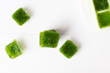 Frozen basil leaves (basilius) in ice cubes with fresh basil on a table. Frozen food concept