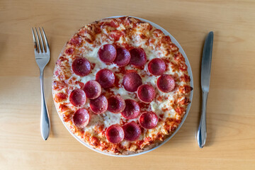 Delicious salami pizza in close-up macro view with cheese and tomato sauce as delicious italian delicacy and diet fast food lunch for hungry teenagers eating unhealthy nutrition snacks in pieces