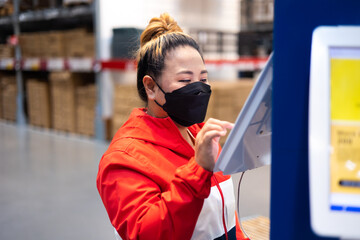 Fat woman worker inspecting stock of products while working in large warehouse. face mask during coronavirus and flu outbreak. Virus and illness protection