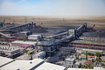 Train on coal unloading station. Coal-harvester loading coal on conveyor to transport to electricity plant. GRES-1 thermal power station. Dry steppe on bckgd. Ekibastuz, Pavlodar region, Kazakhstan.