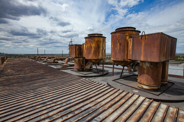 On the roof of heat electric plant. Old rusted pipes of ventilation system. Blue sky with clouds....