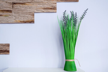 Artificial green colored houseplant stands on wooden shelf at home or cafe interior