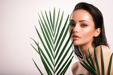 Young beautiful woman with green leaves near face and body. Skin care beauty treatments concept. ...