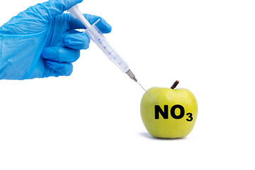 A hand in a medical glove inserts a syringe into a green apple with an inscription NO3 on a white...