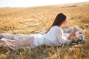 Young woman on a field. Summer is a great dream time. Girl in dress on a field at sunset