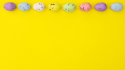 Easter vibrant colorful eggs on top of bright yellow background. Creative copy space. Flat lay minimal arrangement