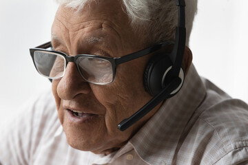 Face of old senior 80s man in glasses, headphones speaking at mic, talking on video call, holding virtual conversation, attending online learning conference, meeting, webinar. Internet communication