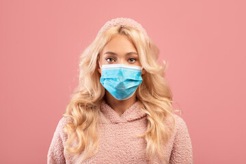 Health care and flu concept. Portrait of young lady wearing surgical face mask and looking at...