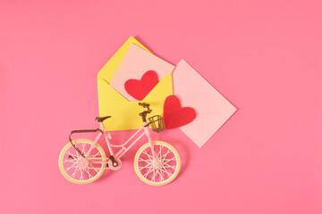Toy bike in vintage style, two red felt hearts and postcard in a pink envelope
