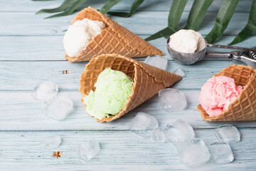 Pastel ice cream in waffle cones, bright blue wooden background