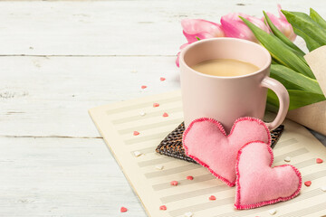 Romantic flat lay composition with a cup of coffee, soft felt hearts, and fresh tulips