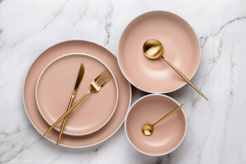 Dishes and utensils for serving and eating meals. Beige round rimmed plates and gold colored...