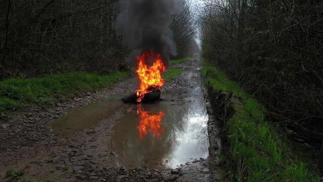 Protesters burn car tires on a country road. Fire, black smoke, strong odor and release of toxic gases. Video flying drone.