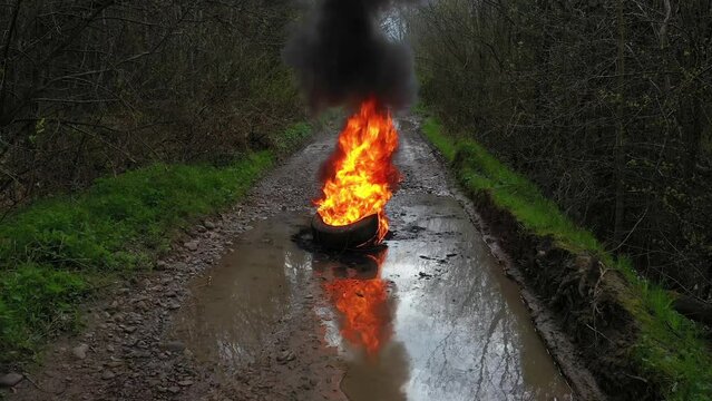 Protesters burn car tires on a country road. Fire, black smoke, strong odor and release of toxic gases. Video flying drone.