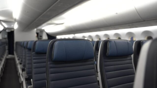Dolly on rows of empty blue airplane seats on a commercial passenger airplane.