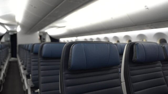 Rows of blue leather airplane seats in a widebody commercial passenger airplane.
