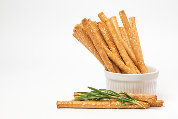 Classic crispy Italian bread sticks with rosemary and sesame seeds in white form. Traditional breadsticks grissini on white background with copy space