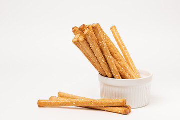 Classic crispy bread sticks grissini with sesame seeds in white form. Traditional Italian pastry breadsticks on white background with copy space